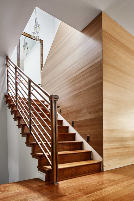Wooden staircase with metal balusters and pendant light.