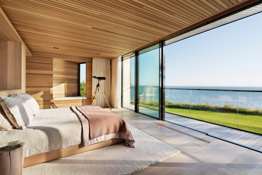 Sleek bedroom with wooden finish and panoramic ocean view.