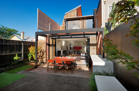Modern backyard with outdoor dining area and open concept house.