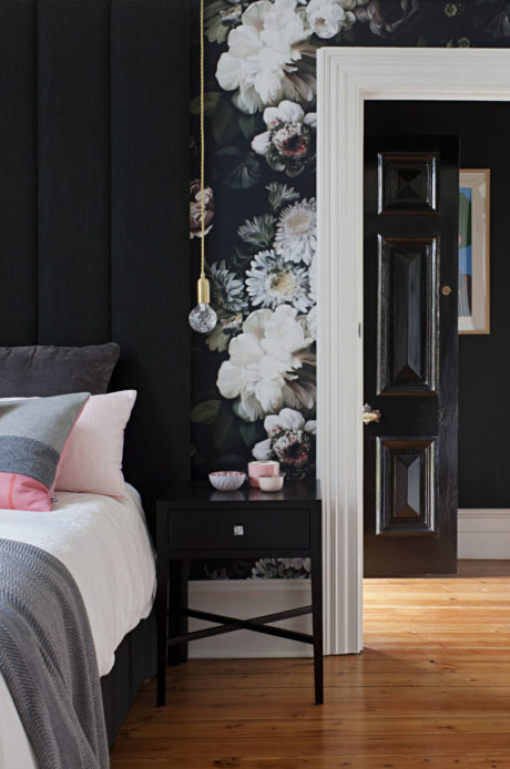 Stylish bedroom with floral wall and dark wood accents.