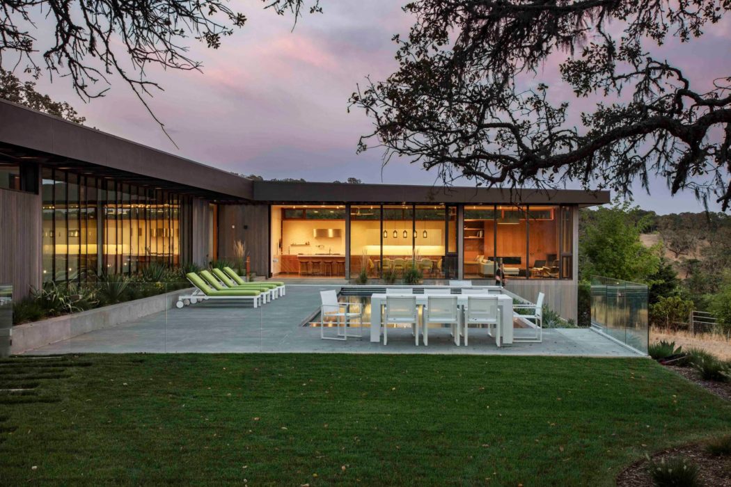 Contemporary home with expansive glass walls and outdoor dining.