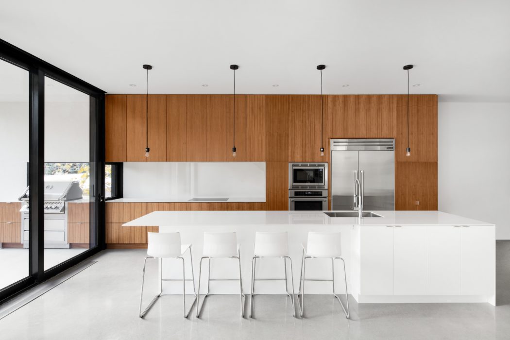 Sleek kitchen interior with wooden cabinets and a white island.