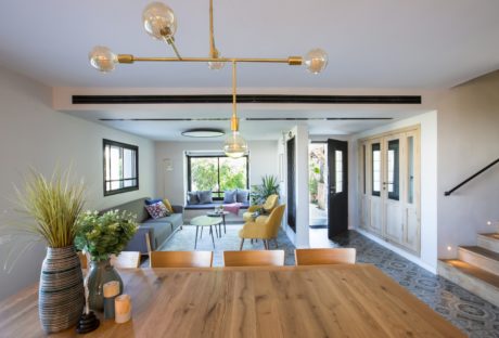 Modern living room with wooden floors, trendy furniture, and decorative lighting.