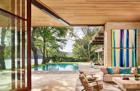 Sleek lakeside living space with expansive windows and pool.