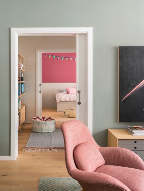 A modern room with a pink armchair, open door to a bright room,