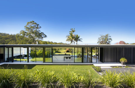 Contemporary glass-walled house overlooking a lush meadow.