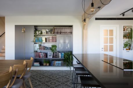 Contemporary dining area with bookshelf, patterned floor, and large table.