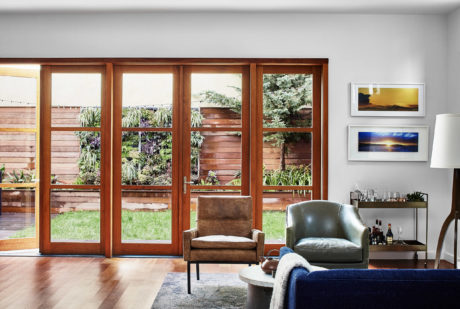 Contemporary living room with large wooden-framed windows overlooking a garden.