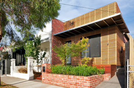 Modern house with brick and wooden slat exterior, front garden, under blue sky