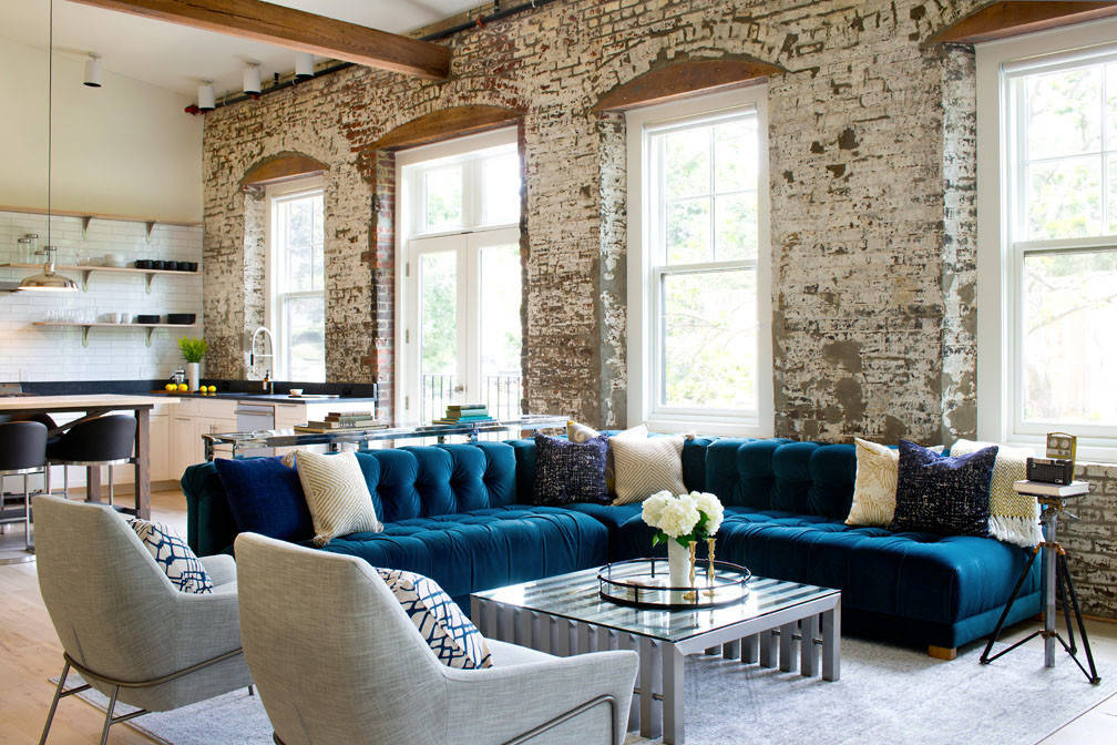 Chic living space with exposed brick walls, a plush blue sofa, and contemporary