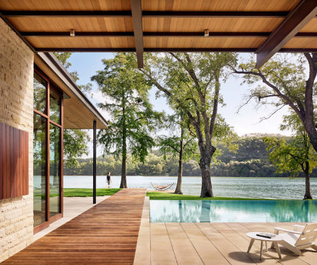 Contemporary lakeside home with infinity pool, wooden deck, and large windows.
