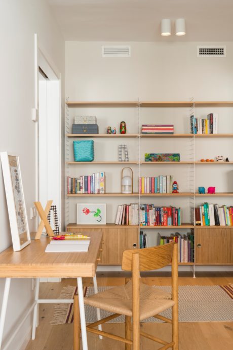 Contemporary home office with wall-mounted shelves and wooden desk.