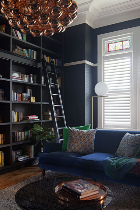 Elegant reading nook with blue sofa, copper pendant light, and booksh