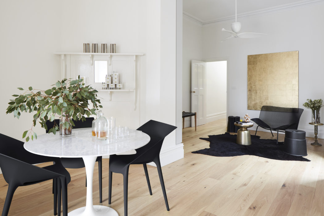 Modern, minimalistic dining and living room with white walls and wood flooring.