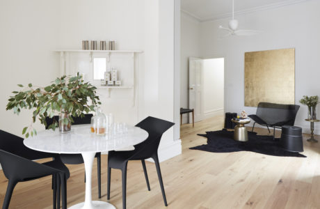 Modern, minimalistic dining and living room with white walls and wood flooring.