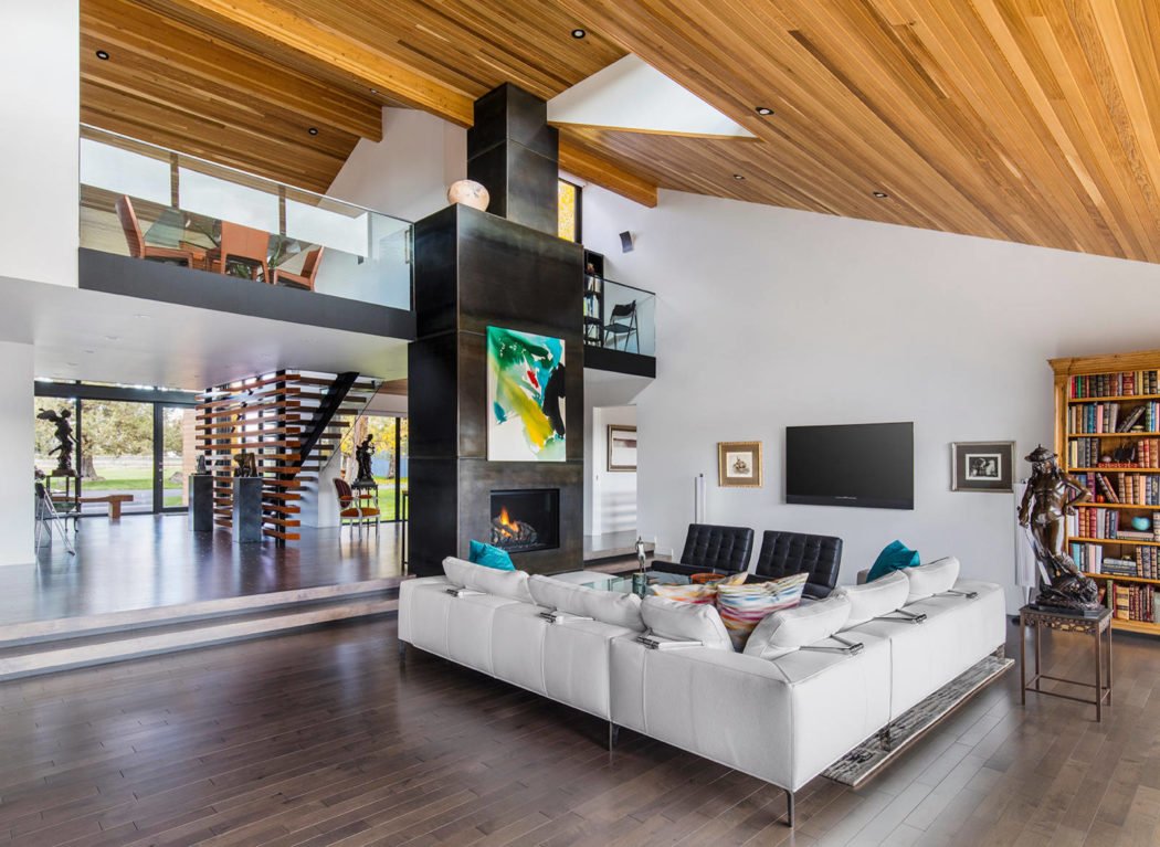 Modern living room with a white sectional sofa, wooden ceiling, and a spiral staircase
