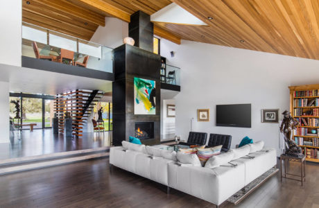 Modern living room with a white sectional sofa, wooden ceiling, and a spiral staircase