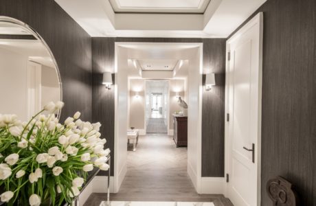 Modern hallway design with dark wallpaper, mirror, and white doors.