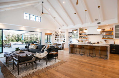 Open concept living room and kitchen with modern furniture and wooden floors.