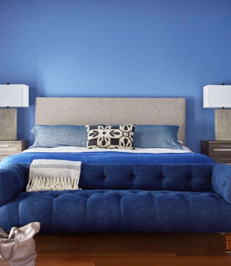 Blue bedroom with a tufted bed and matching bedding.
