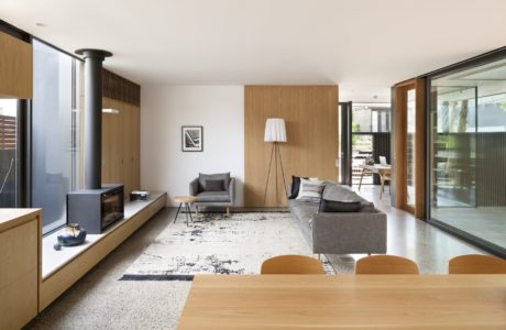 Minimalist living space with wood paneling and large glass doors.