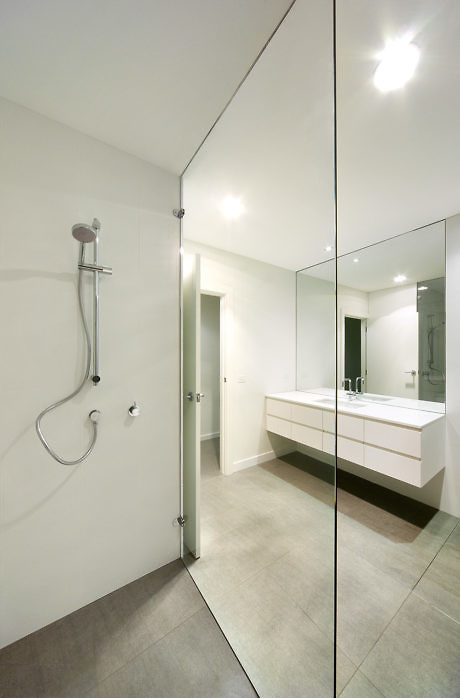 Minimalist bathroom with glass shower partition and floating vanity.