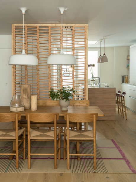 Contemporary dining space with wooden table, pendant lights, and slatted room divider