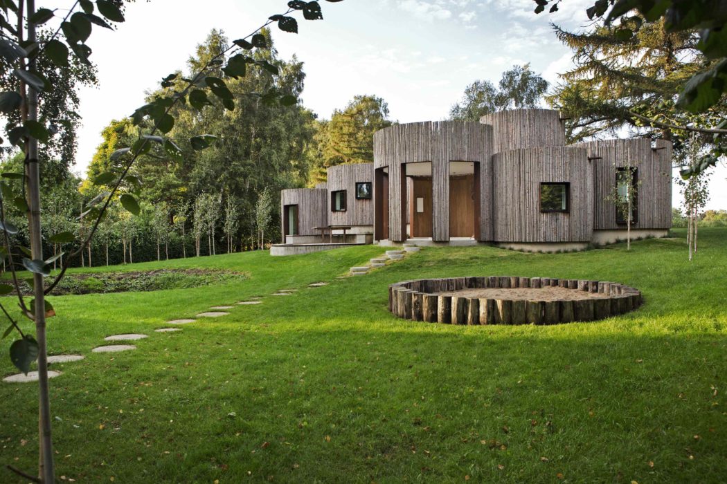 Contemporary wooden house with stepping stone pathway and circular lawn feature.