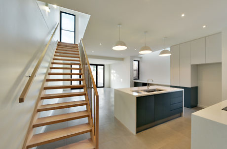 Contemporary open-concept home interior with stairs and kitchen.
