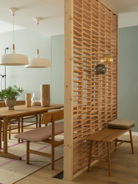Modern dining area with wooden lattice partition and pendant lighting.