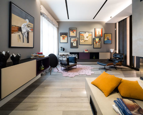 Modern living room with artworks on walls, stylish furniture, and decorative cushions.