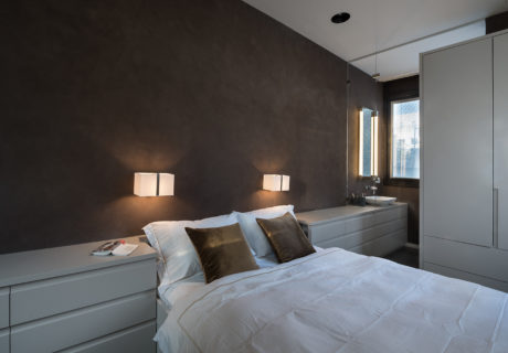 Contemporary bedroom with sleek furnishings and warm lighting.