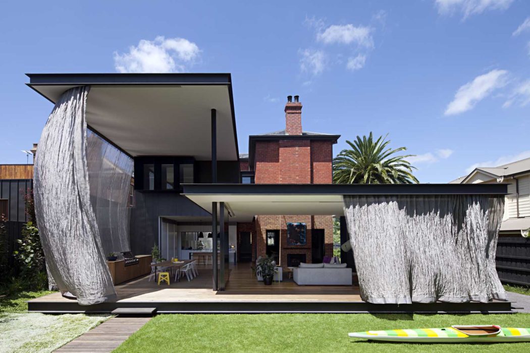Contemporary house with large fabric screens and a classic brick chimney.