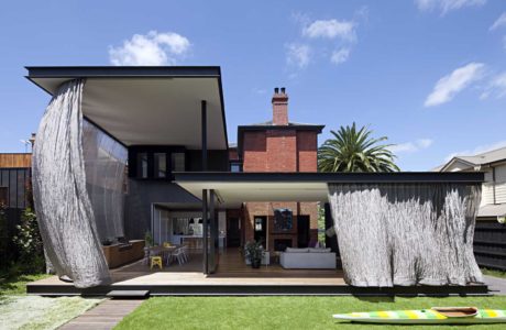 Contemporary house with large fabric screens and a classic brick chimney.