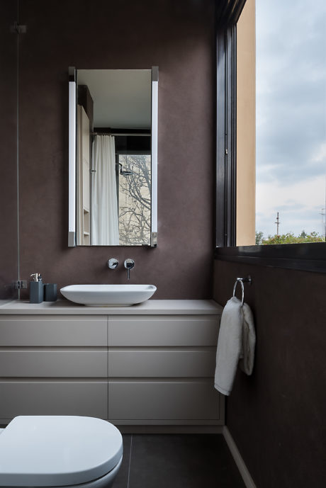 Modern bathroom with beige cabinets, sink, mirror, and window with tree view.