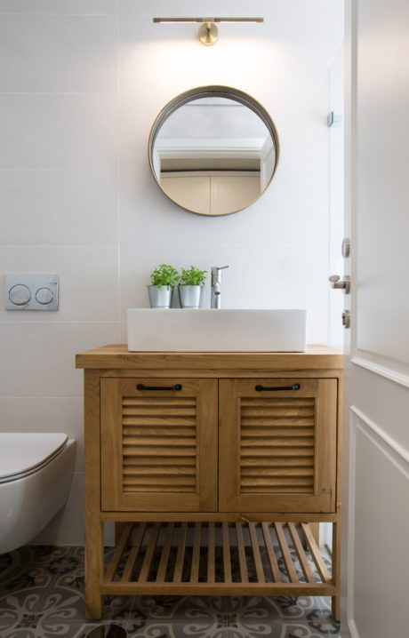 Modern bathroom vanity with wooden cabinet, vessel sink, and round mirror.