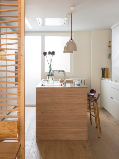 Bright minimalist kitchen with wooden island and pendant light.