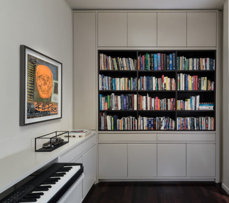 Sleek home office with bookshelves, piano, and framed artwork.