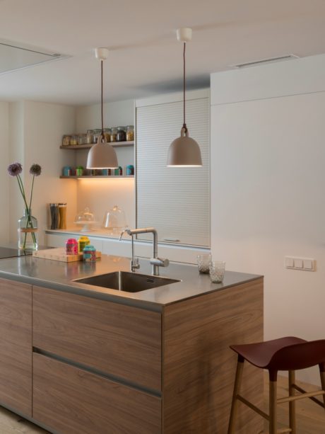 Modern kitchen with wooden cabinets and pendant lights.