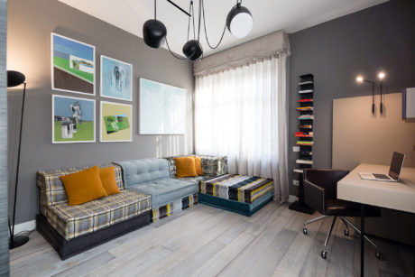 Modern living room with a gray sofa, art on the wall, and a small