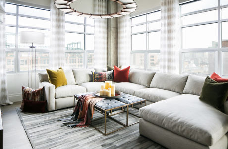 Modern living room with large sectional sofa, coffee table, and floor-to-ceiling