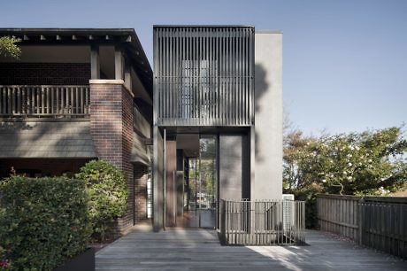 Modern two-story house with a metal facade and large windows.