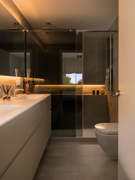 Sleek bathroom with warm lighting, glass shower, and floating vanity.