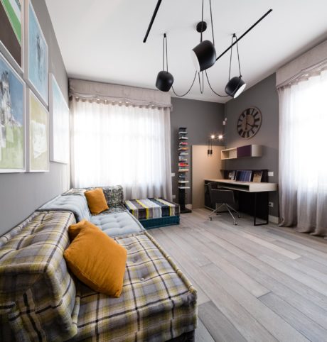 Modern room interior with plaid sofa, pendant lights, desk, and wall clock