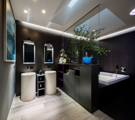 Modern bathroom with dark wood walls, a large mirror, and white accents.