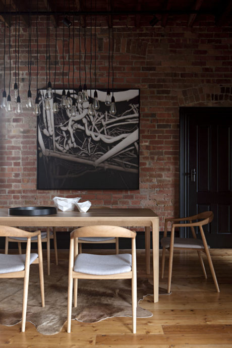 Dining room with exposed brick wall, modern art, and unique pendant lights.