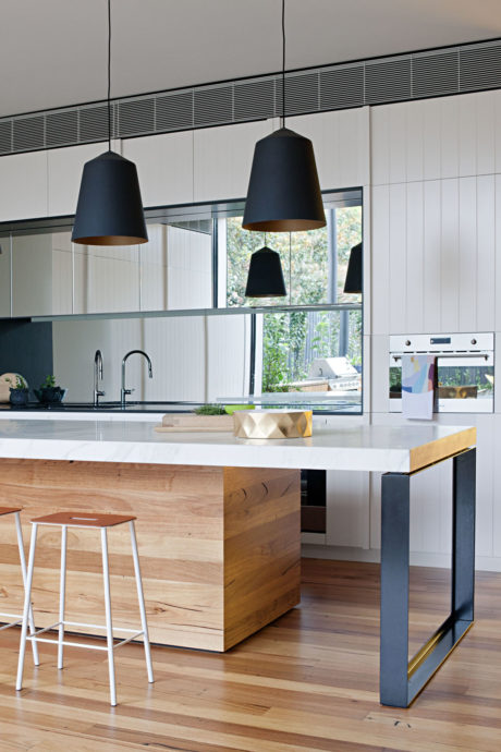 Contemporary kitchen with wood island, black pendant lights, and white cabinetry.