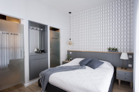Contemporary bedroom with patterned wall and labeled glass doors.