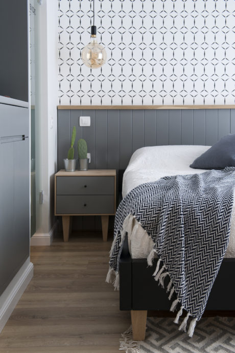 Stylish bedroom with geometric wallpaper and chic pendant light.