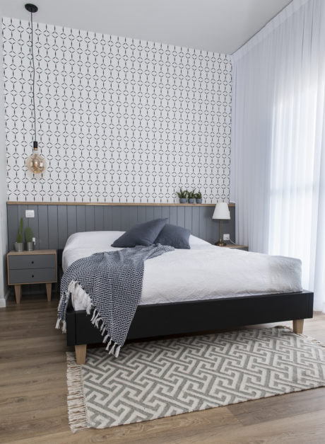Modern bedroom with patterned wallpaper and stylish pendant light.